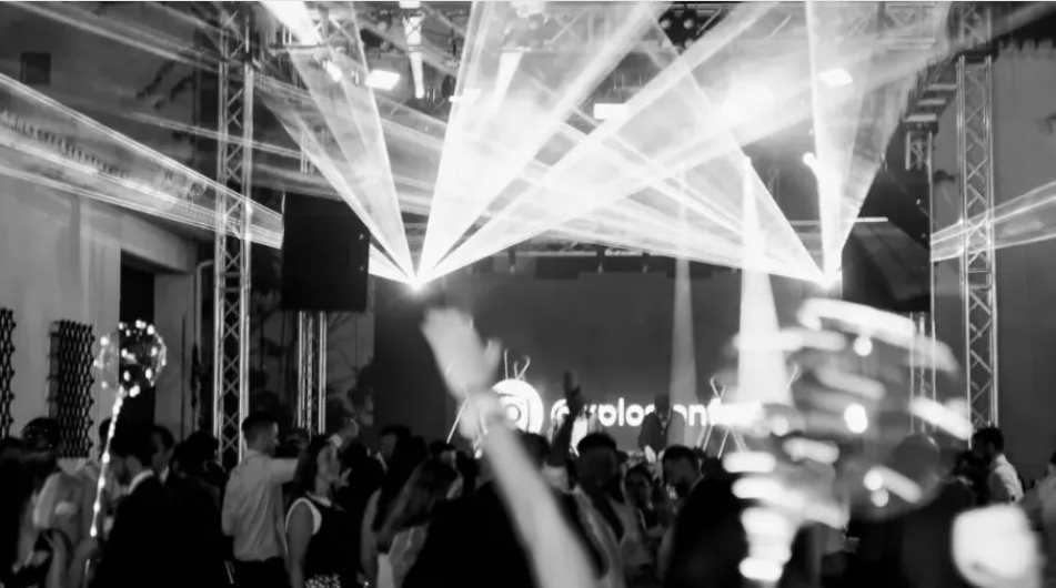 Invitados bailando en la pista de una boda bajo haces de láser, en blanco y negro