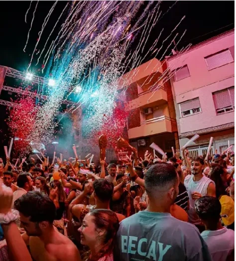 Público bailando bajo lluvia de confeti y luces de colores