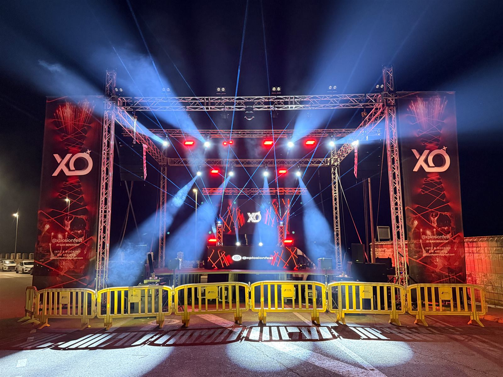 Escenario con truss, focos de luz azul y lonas laterales montado al aire libre